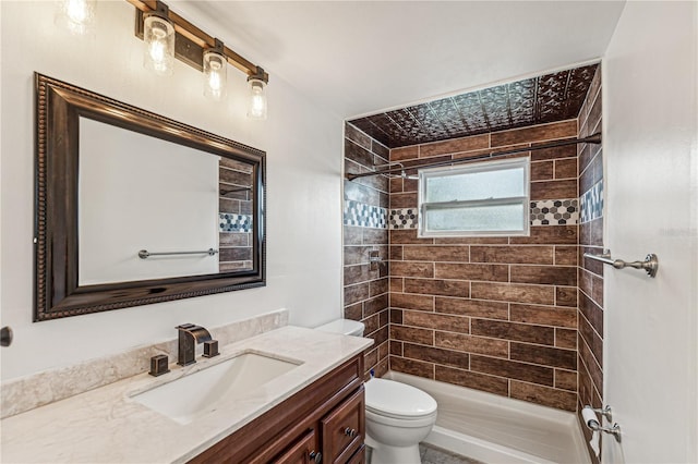 bathroom with toilet, tiled shower, and vanity