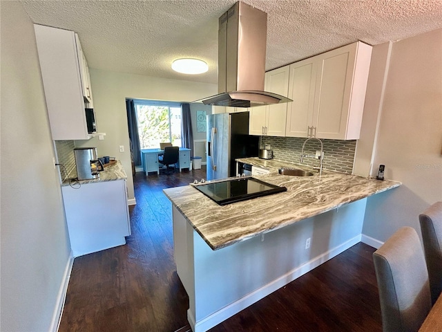 kitchen featuring stainless steel fridge, island range hood, kitchen peninsula, and white cabinets