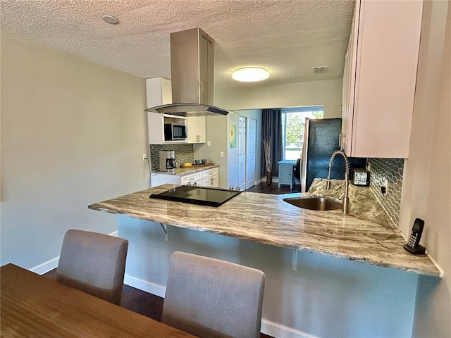 kitchen featuring backsplash, island range hood, stainless steel refrigerator, and sink