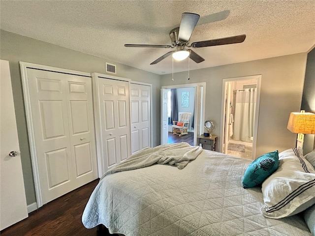 bedroom with multiple closets, ceiling fan, dark hardwood / wood-style floors, ensuite bathroom, and a textured ceiling