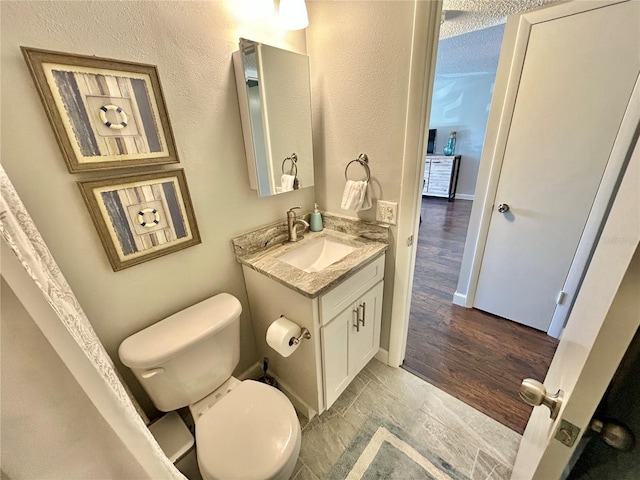 bathroom with hardwood / wood-style floors, vanity, a textured ceiling, and toilet