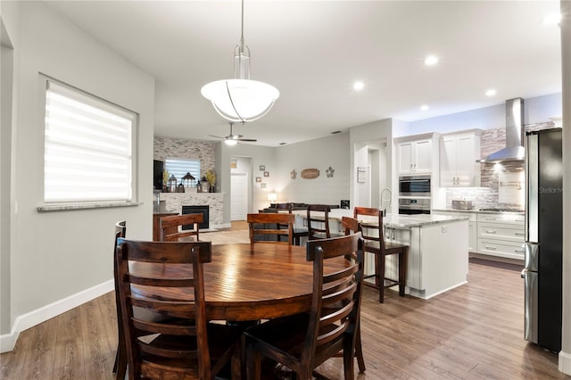 dining area with ceiling fan, a fireplace, and hardwood / wood-style flooring