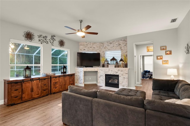 living room with ceiling fan, light hardwood / wood-style flooring, and a tile fireplace