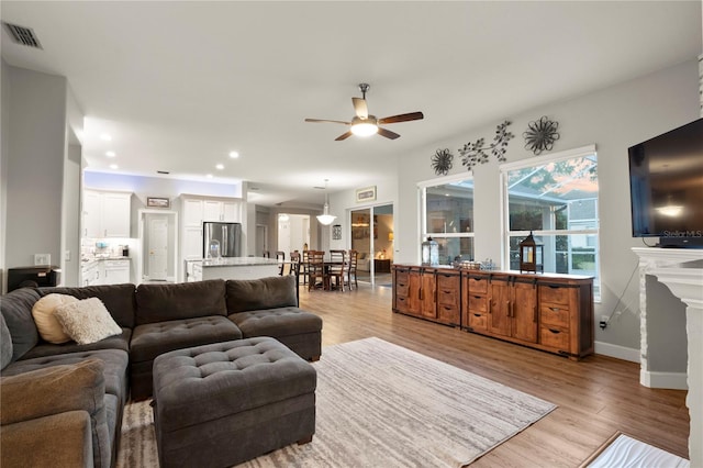 living room with ceiling fan and light wood-type flooring