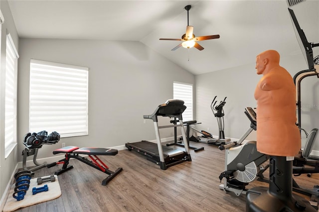 workout room with ceiling fan, vaulted ceiling, and light hardwood / wood-style floors