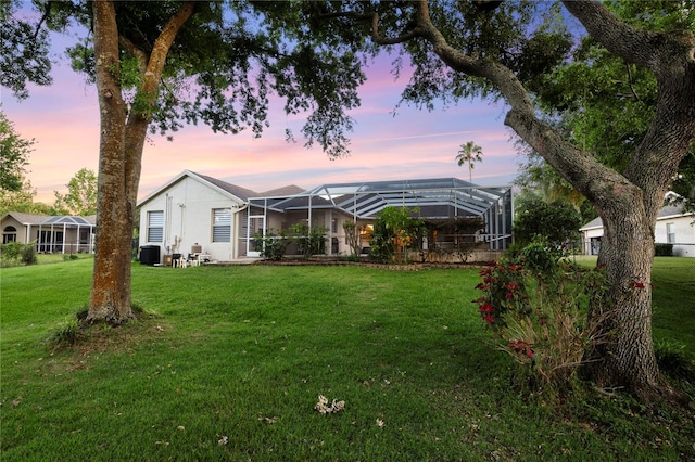 yard at dusk with a lanai and cooling unit