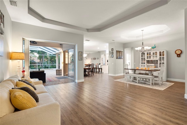 living room with a tray ceiling, dark hardwood / wood-style floors, and an inviting chandelier