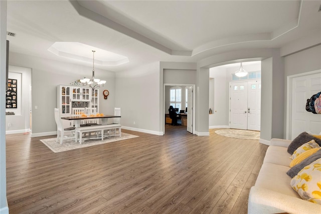 living room featuring dark hardwood / wood-style flooring, a raised ceiling, and a chandelier