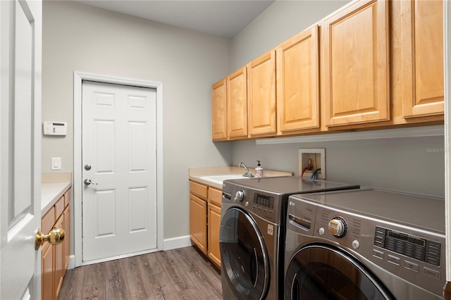 clothes washing area with dark wood-type flooring, cabinets, washer and clothes dryer, and sink