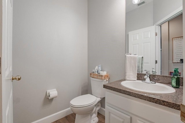 bathroom with wood-type flooring, toilet, and vanity