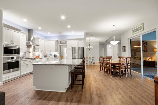 6020 Kestrel Point Ave, Lithia, FL 33547 - kitchen with wall chimney exhaust hood, light wood-type flooring, light stone counters, backsplash, and white cabinetry