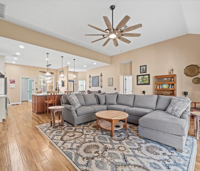 living room featuring ceiling fan, vaulted ceiling, and light wood-type flooring