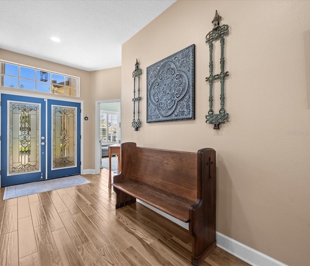 entryway with wood-type flooring, a textured ceiling, and french doors