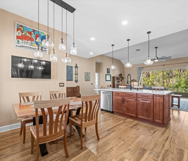 kitchen featuring vaulted ceiling, stainless steel dishwasher, ceiling fan, an island with sink, and decorative light fixtures