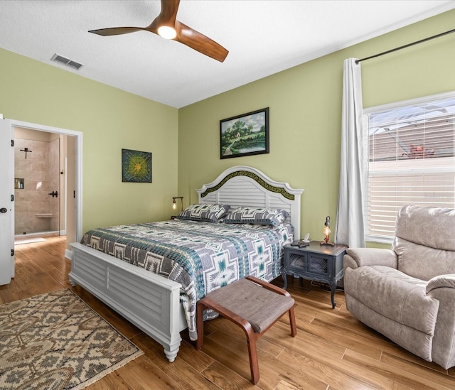 bedroom featuring ceiling fan, light wood-type flooring, a textured ceiling, and connected bathroom