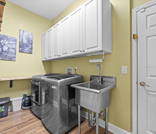 laundry area with cabinets, light wood-type flooring, and washer and dryer