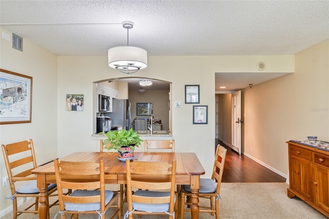 dining room featuring carpet floors, sink, and a textured ceiling