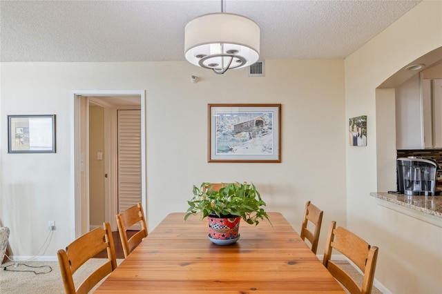 carpeted dining area with a textured ceiling