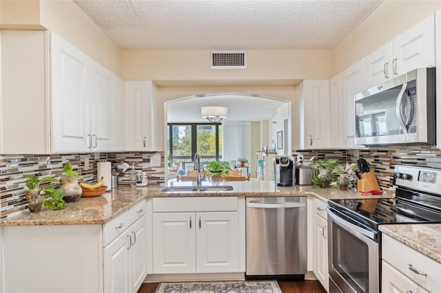 kitchen with white cabinets, appliances with stainless steel finishes, sink, and a textured ceiling