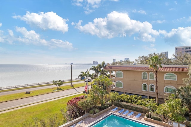 view of pool with a lawn and a water view