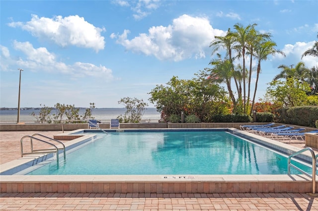 view of pool with a patio area and a water view