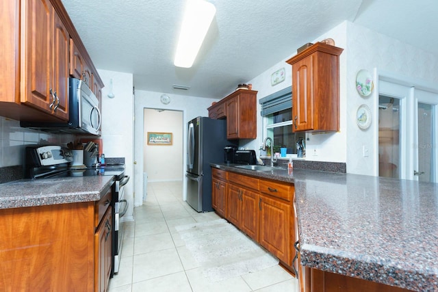 kitchen featuring a textured ceiling, stainless steel appliances, light tile patterned floors, tasteful backsplash, and sink