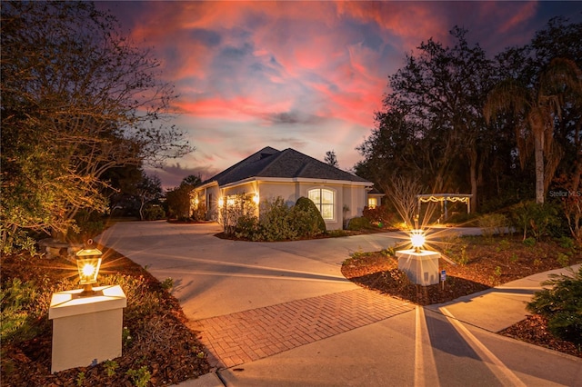 view of front of home with decorative driveway, a fire pit, and stucco siding