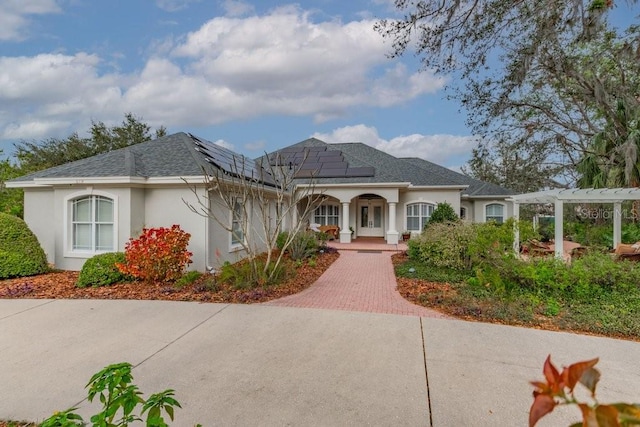 view of front of property featuring solar panels, roof with shingles, covered porch, a pergola, and stucco siding