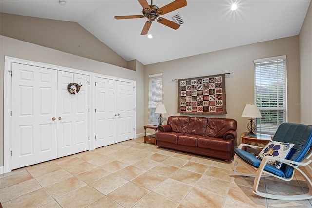 living area featuring ceiling fan, light tile patterned floors, visible vents, baseboards, and vaulted ceiling