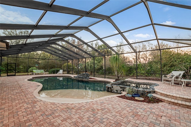 view of pool with glass enclosure, a patio area, and a pool with connected hot tub