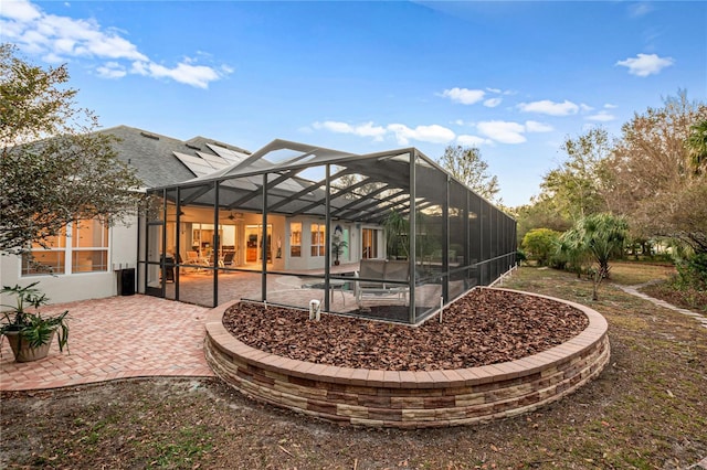 back of house featuring a patio area, glass enclosure, and a ceiling fan