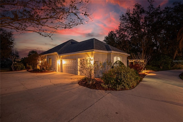 view of front of house with a shingled roof, a garage, driveway, and stucco siding