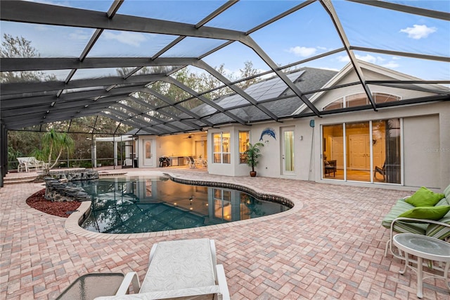 outdoor pool featuring glass enclosure and a patio area