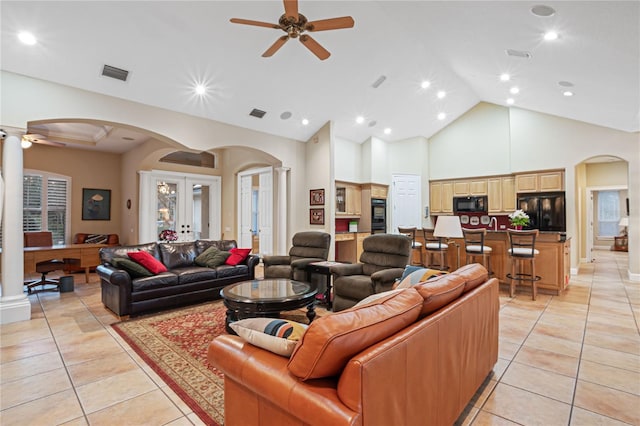 living area with light tile patterned floors, visible vents, arched walkways, and decorative columns