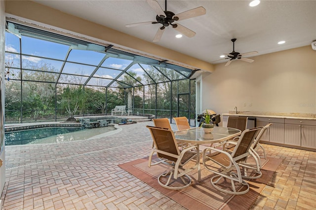 view of patio / terrace with a pool with connected hot tub, ceiling fan, glass enclosure, outdoor dining area, and a sink