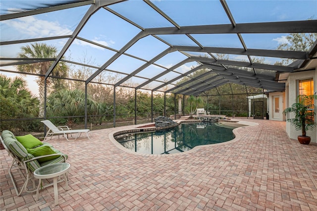 pool with glass enclosure, a patio, and a hot tub