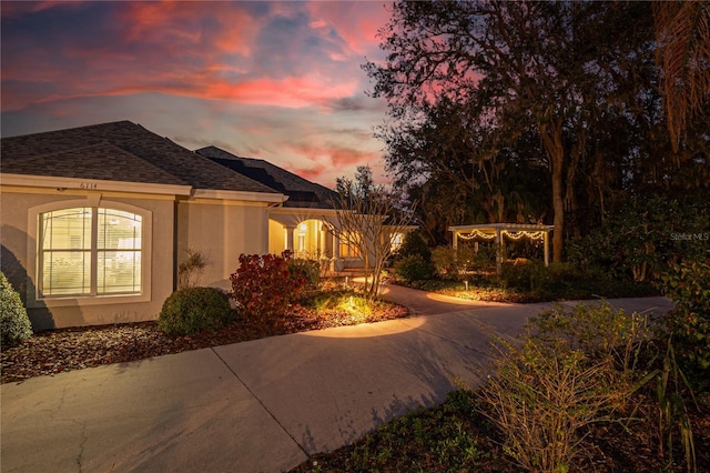 view of front of home featuring stucco siding and roof with shingles