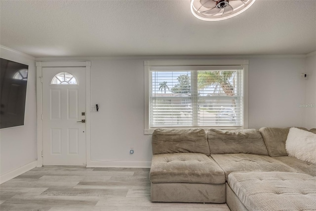 foyer entrance with a textured ceiling, light hardwood / wood-style flooring, and crown molding