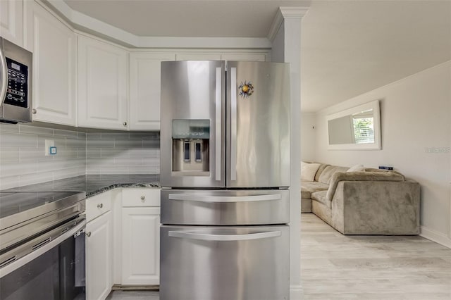 kitchen with backsplash, white cabinetry, stainless steel appliances, and light hardwood / wood-style flooring