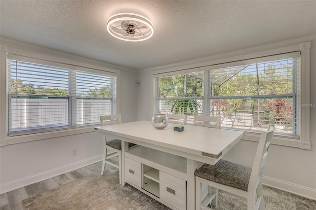 dining area with a textured ceiling, light hardwood / wood-style floors, and crown molding