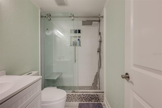 bathroom with vanity, toilet, a shower with door, and a textured ceiling