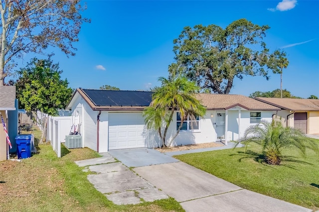 view of front of property featuring solar panels, central AC unit, a front lawn, and a garage