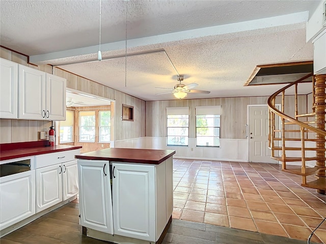 kitchen with white cabinets, ceiling fan, a center island, and a textured ceiling