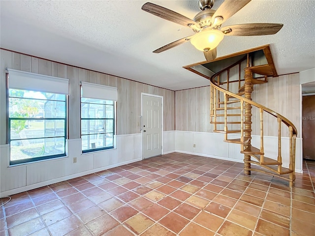 entryway with tile patterned floors, ceiling fan, and a textured ceiling