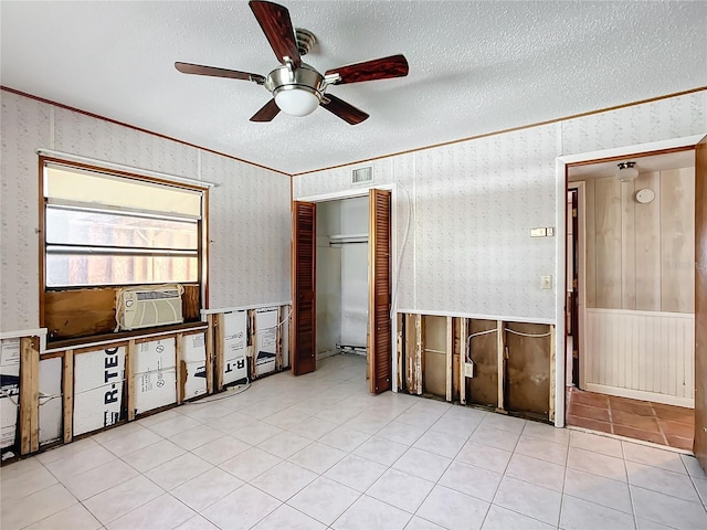 empty room featuring ceiling fan, ornamental molding, a textured ceiling, and light tile patterned floors