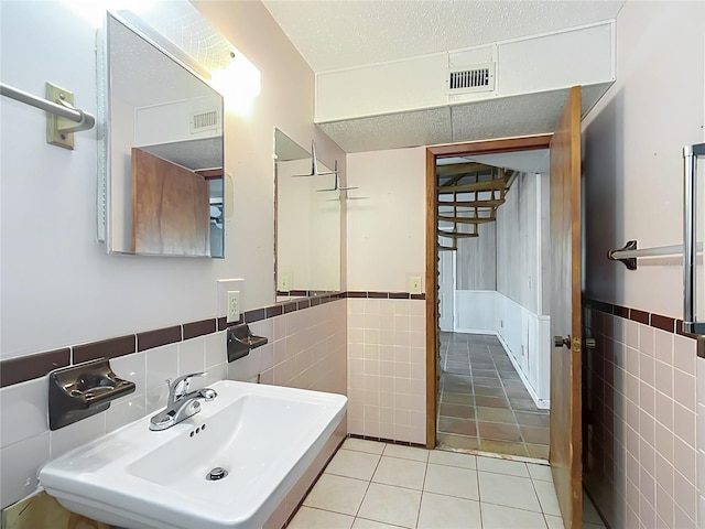 bathroom featuring tile patterned floors, tile walls, and sink