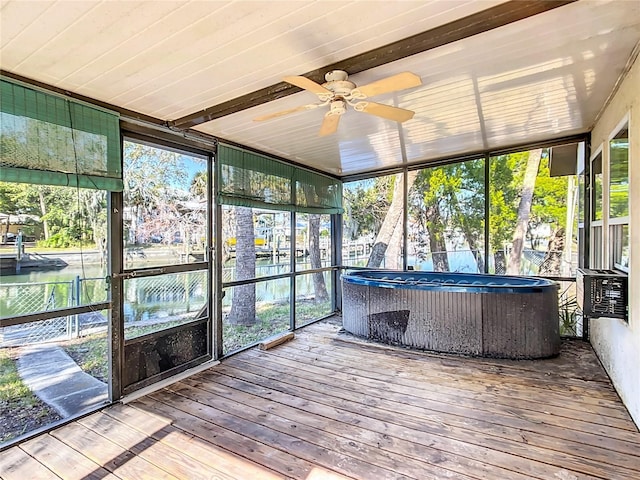 unfurnished sunroom with cooling unit, ceiling fan, and a water view