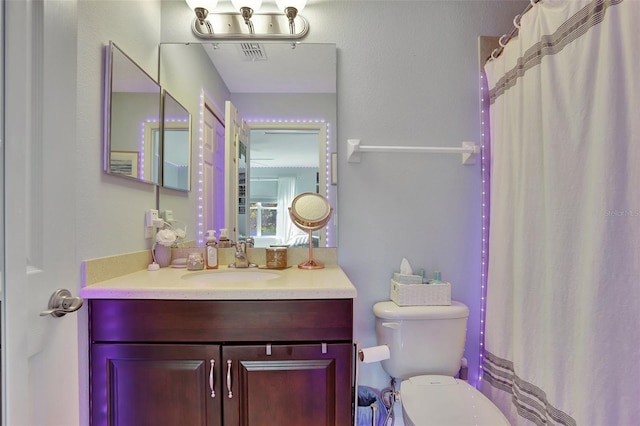 bathroom featuring toilet, a shower with shower curtain, and vanity