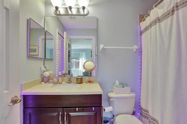 bathroom featuring curtained shower, toilet, and vanity