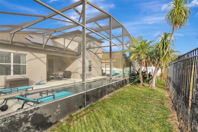 view of pool with glass enclosure, a patio area, and a lawn